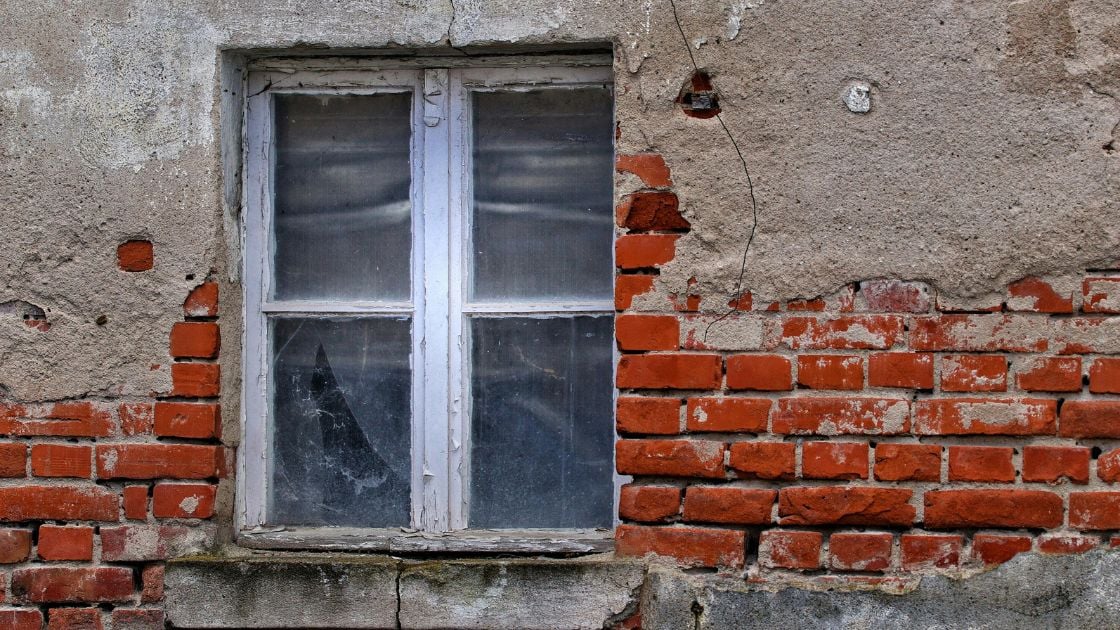 Old window on a weathered brick wall showing the history of windows in homes